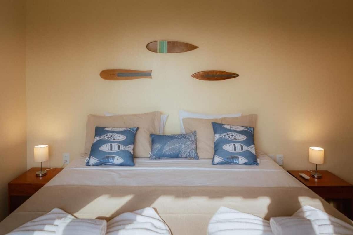 A hotel room with a bed, pillows, nightstands, and wall decor.