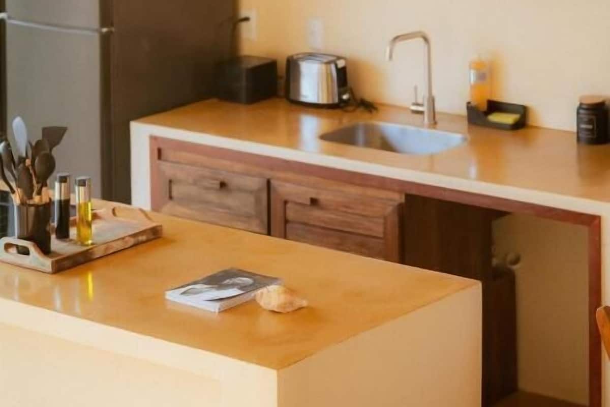 A kitchen with wooden cabinets, a sink, a countertop, and a refrigerator.