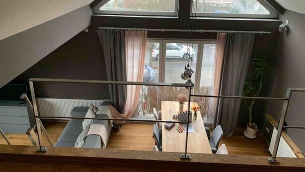 Un espai tipus loft amb sostre alt, taula de dinar i vista al carrer.