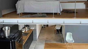 Un dormitori d'estil loft amb sostre inclinat, un llit, una taula de treball i una cadira.