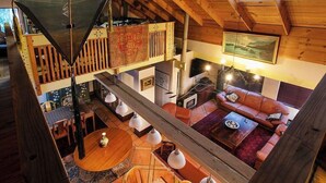 Amplio espacio tipo loft con techo alto, vigas de madera, comedor y una zona de estar acogedora con chimenea.