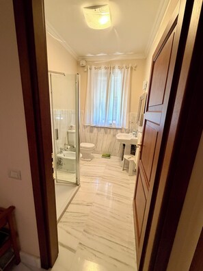 Ein Badezimmer mit Duschkabine aus Glas, Toilette, Waschbecken und Waschtisch.