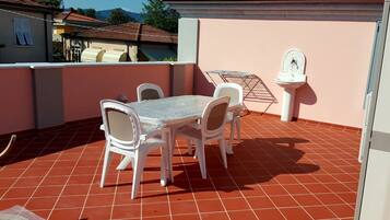 Eine Terrasse mit Tisch und Stühlen, ein kleiner Garten und eine Zierfontäne.