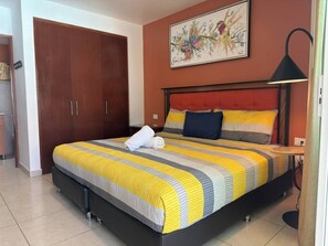 Une chambre à coucher avec un lit, une table de chevet, une lampe, une armoire et un tableau au mur.