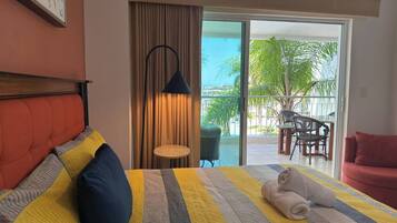 Une chambre d’hôtel avec un lit, un canapé rouge, une petite table et une vue sur l’extérieur.