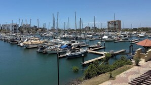 Un port de plaisance où sont amarrés de nombreux bateaux, un ciel dégagé et des bâtiments en arrière-plan.