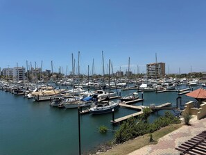 A marina with numerous boats docked, a clear sky, and buildings in the background. - Costa Veleros, Atardeceres Únicos by GPS (Mazatlán)