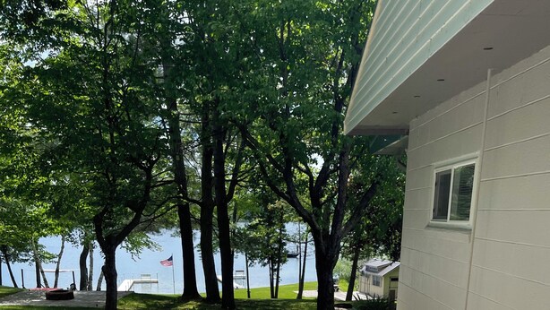 Un sentier pavé de pierres plates mène à une maison située au bord d’un lac, entourée d’arbres.