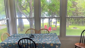 Un coin repas avec une table recouverte d’une nappe bleue ornée de motifs représentant des aliments, entourée de chaises en bois.