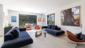 Ein modernes Wohnzimmer mit einer Couch, Sesseln, einem Couchtisch und Kunstwerken an den Wänden.