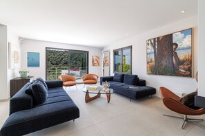 A modern living room with a sofa, armchairs, a coffee table, and artwork on the walls.