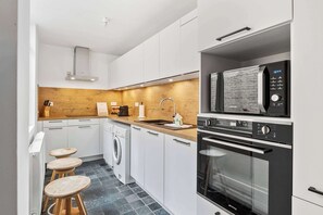 Eine kleine Küche mit Mikrowelle, Backofen und Waschmaschine.