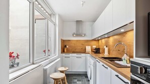 Una cocina moderna con encimera de madera, horno empotrado, lavamanos y ventana con vistas a flores.