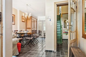 Ein Essbereich mit einer Chandelüster, Holzschränken und einer Treppe, die zu einem grünen Raum führt.