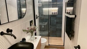 A bathroom with a black sink, a white toilet, a glass shower enclosure, and a mirror. - MAGDALENA APARTMENT (Oviedo)