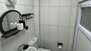 Ett litet, modernt badrum med toalett, bidé, handfat och en spegel.