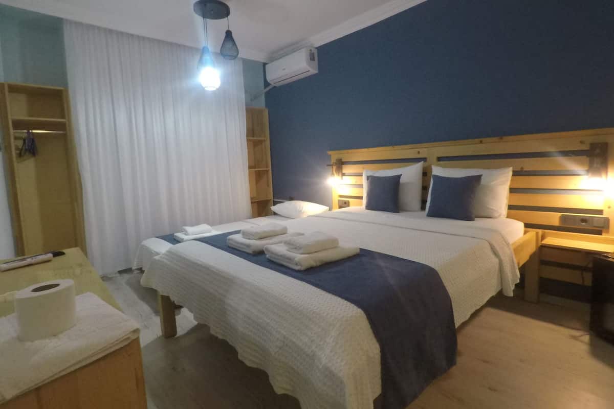 Et hotelværelse med en stor seng, natborde, et garderobeskab og en lampe i loftet.