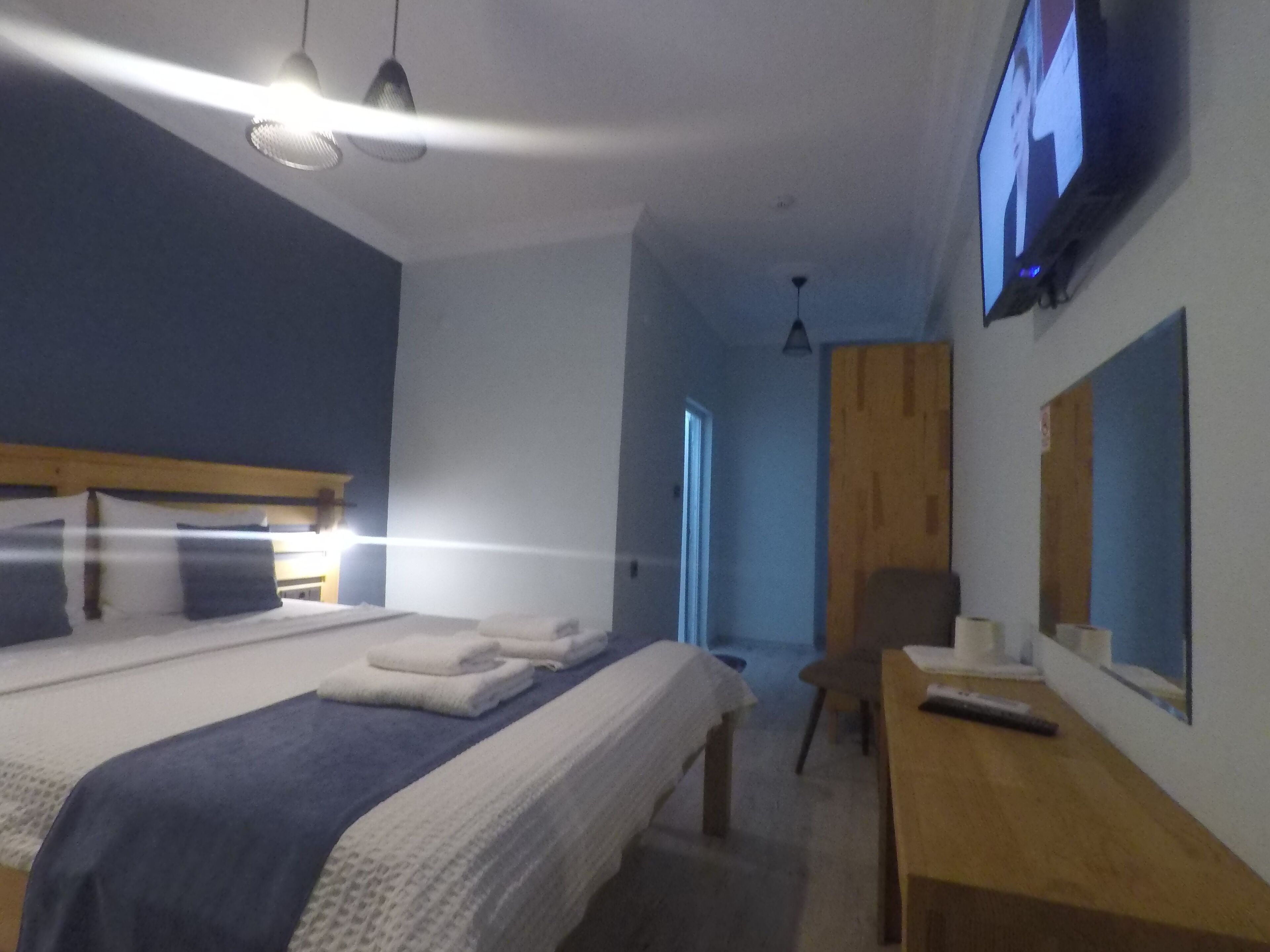 A hotel room with a bed, a desk, a chair, a TV, and a wooden panel on the wall.