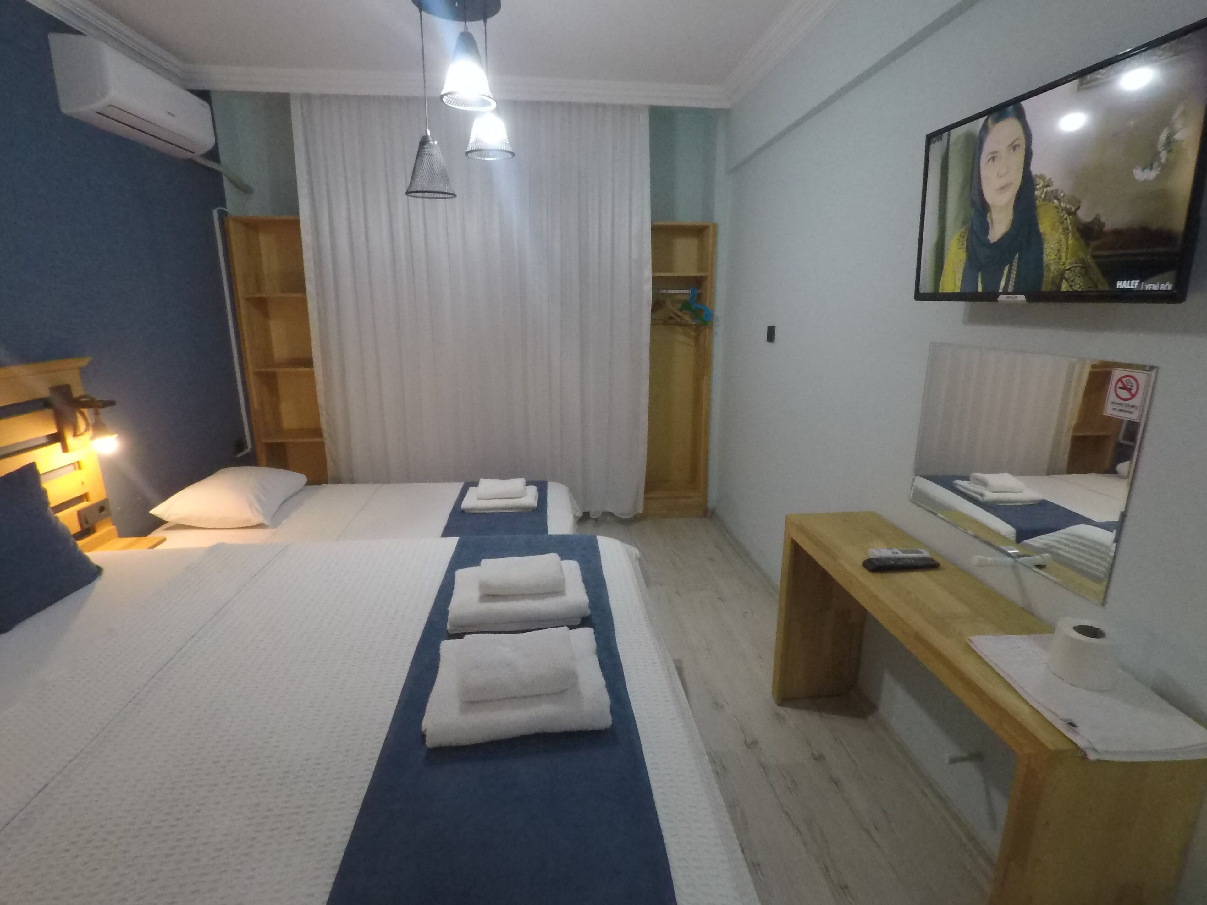 Ein Hotelzimmer mit Bett, Nachttischen, einem Spiegel, einem Fernseher und einem Kleiderschrank.