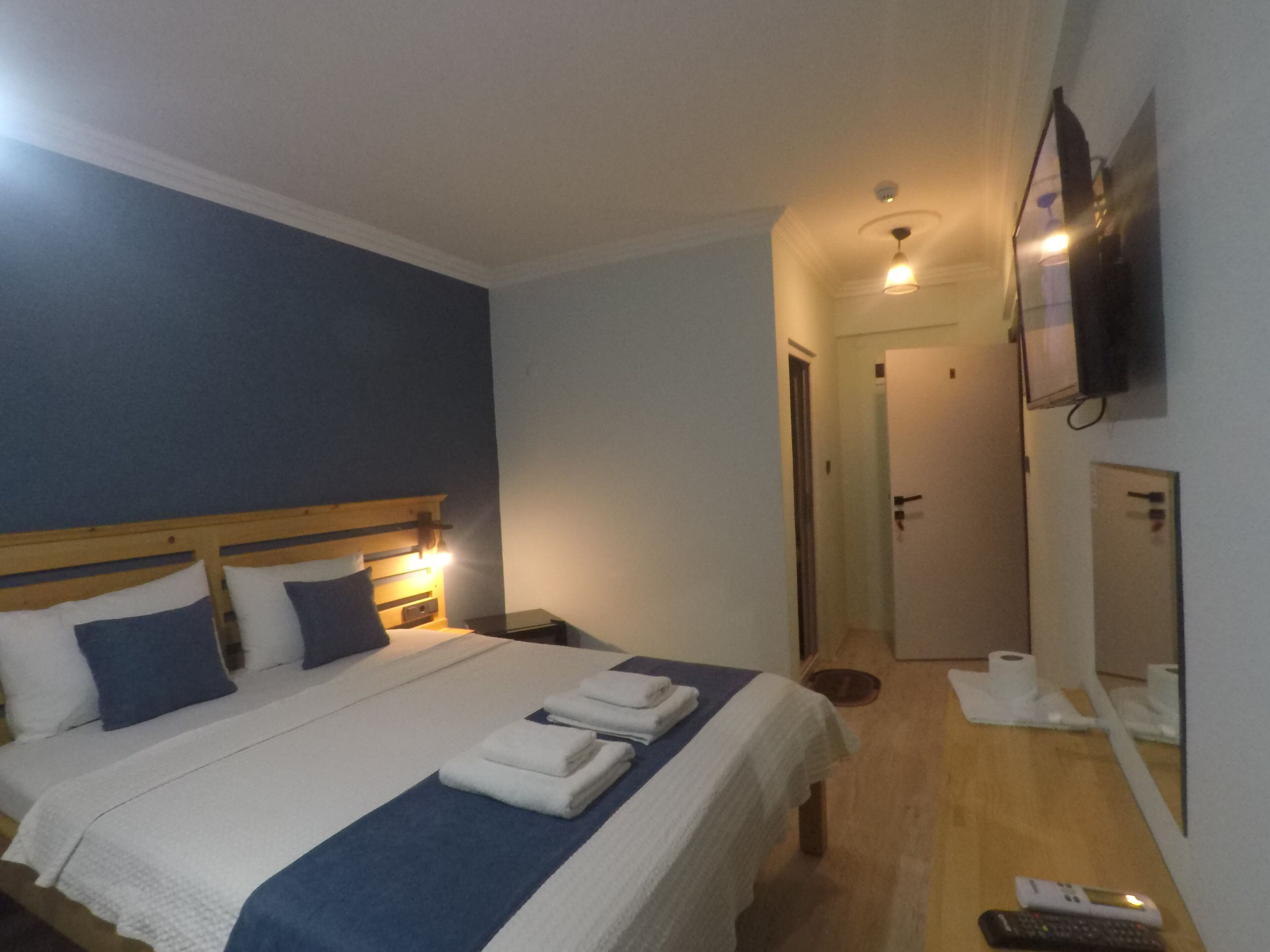 Ein Hotelzimmer mit Bett, Nachttischen, Fernseher, Spiegel und einer Badezimmertür.