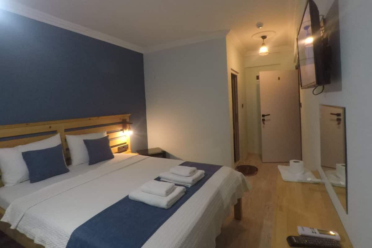 Ein Hotelzimmer mit Bett, Nachttischen, Fernseher, Spiegel und einer Badezimmertür.