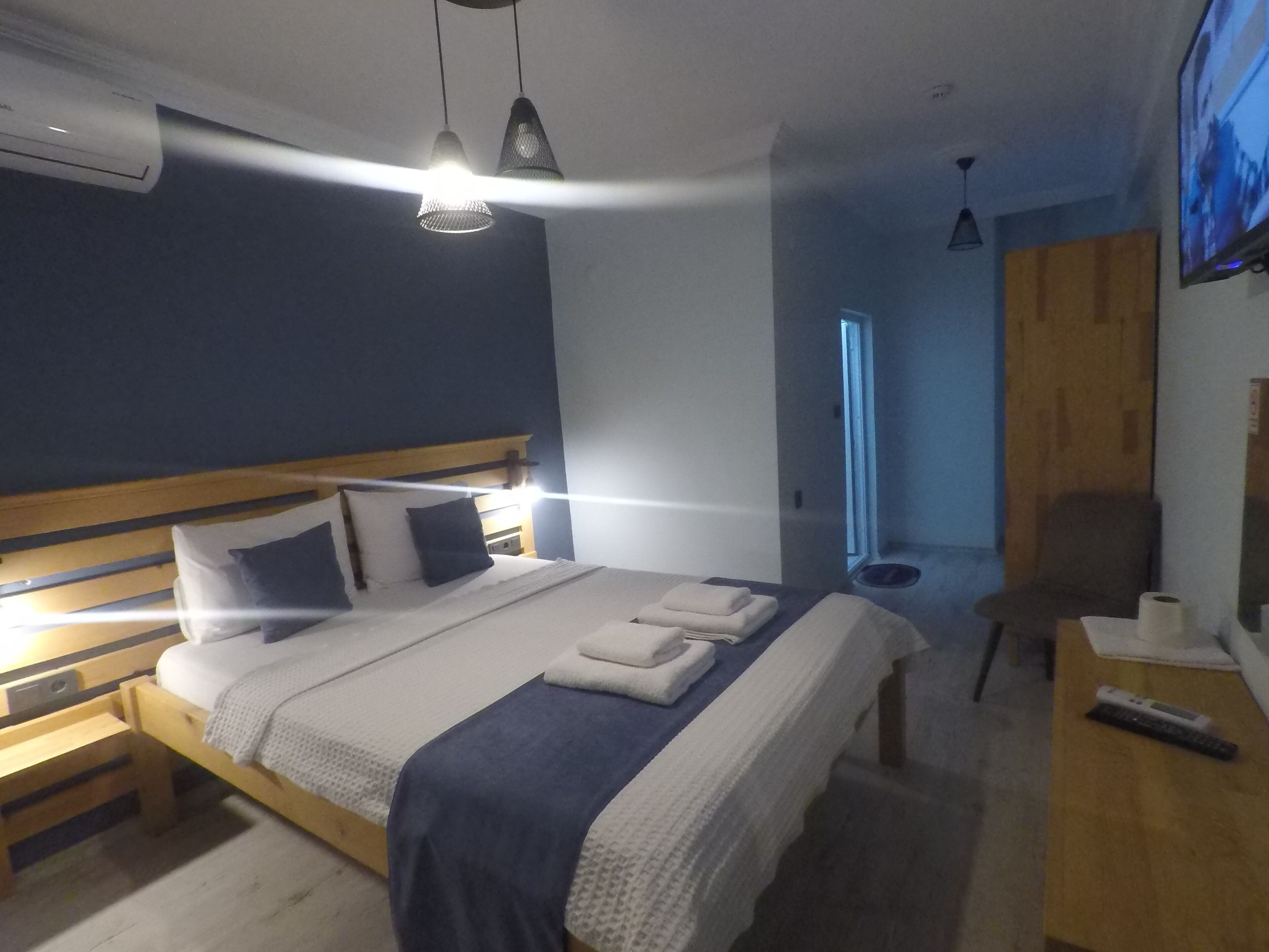 A bedroom with a bed, bedside tables, a TV, and an air conditioning unit.