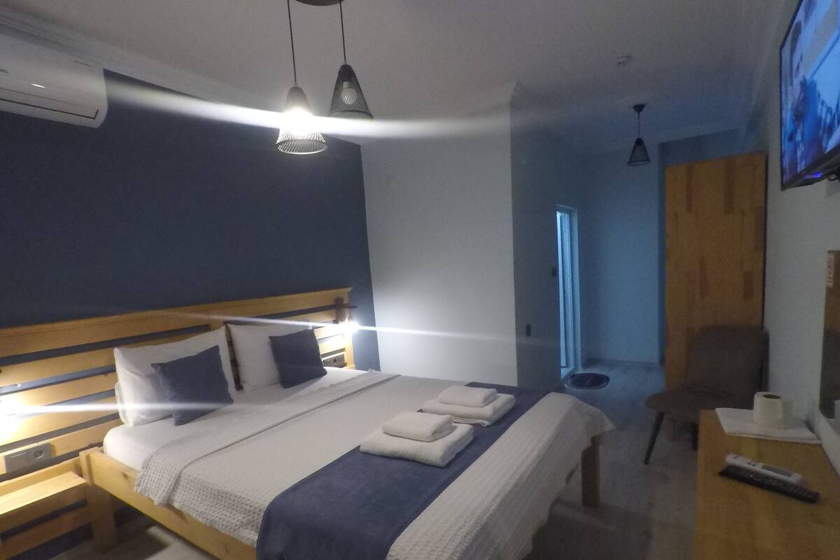 A bedroom with a bed, bedside tables, a TV, and an air conditioning unit.