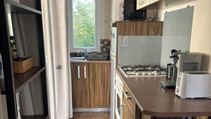 Moderni keittiö, jossa on puukalusteet, kaasuliesi, mikroaaltouuni ja leivänpaahdin.
