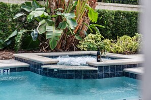 A hot tub with a tiled edge, surrounded by lush greenery and a pool. - 9Br Spacious Villa With Private Pool Close Disney (Kissimmee)