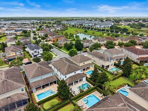 A residential area with houses, a swimming pool, and a golf course in the background. - 9Br Spacious Villa With Private Pool Close Disney (Kissimmee)