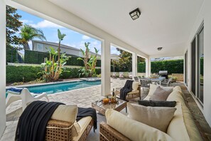 Ett takförsett utomhusområde med en pool, solstolar och ett matbord.