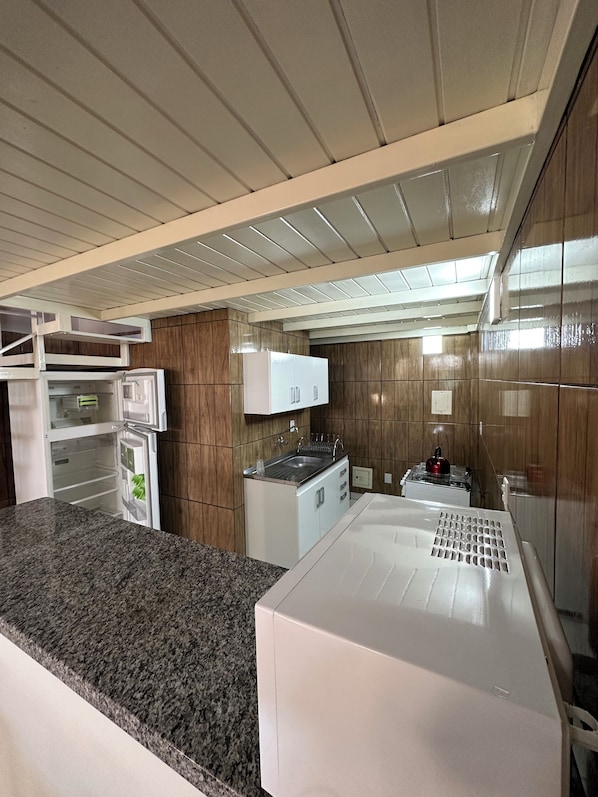 A modern kitchen with a granite countertop, white cabinetry, and a built-in oven. - Palmares Hotel (Palmares do Sul)