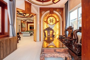 Un lobby lujoso con mesa de billar, muebles de madera ornamentados y una gran puerta en arco.