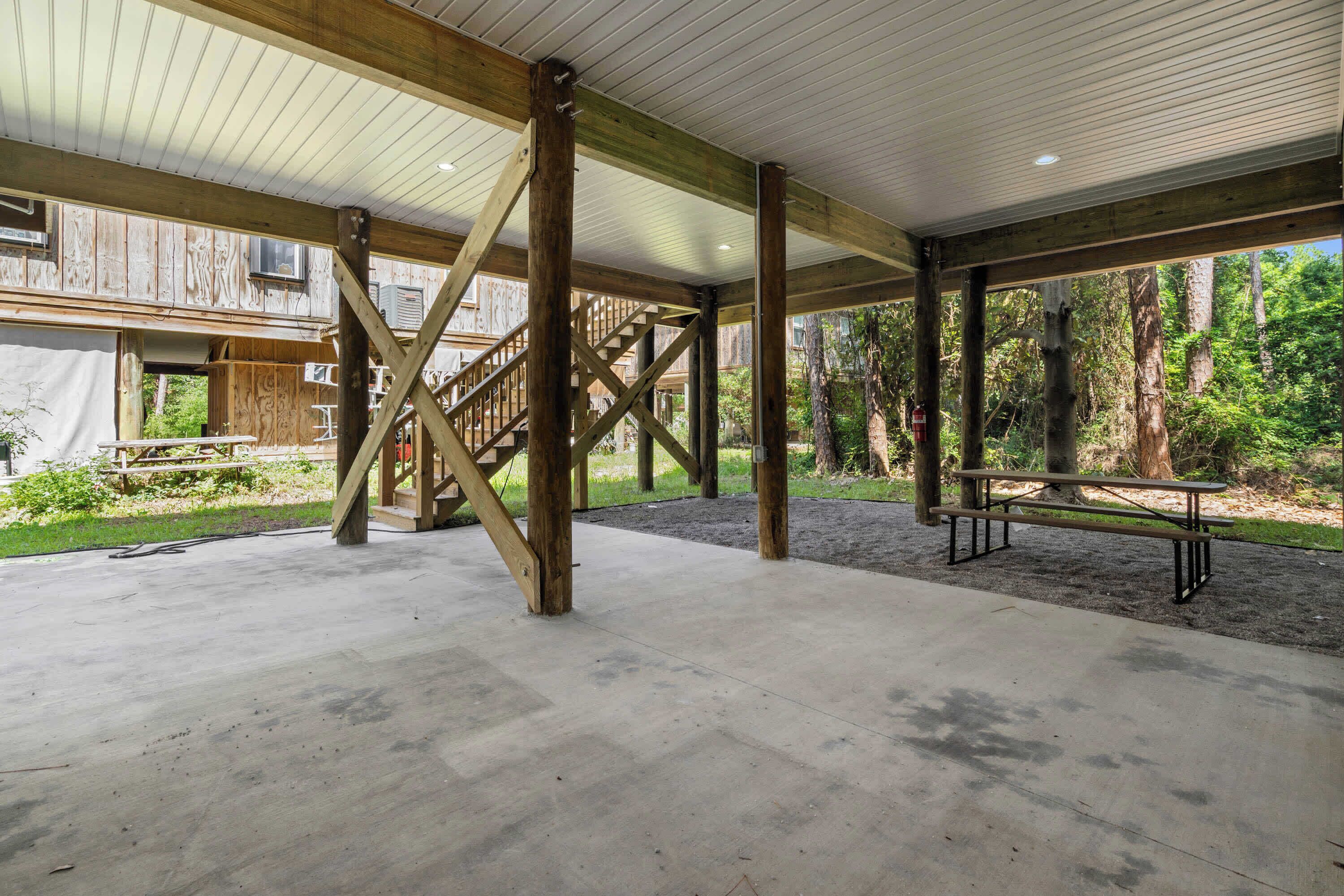 Ein überdachter Außenbereich mit Betonboden, Holzbalken und einer Treppe.