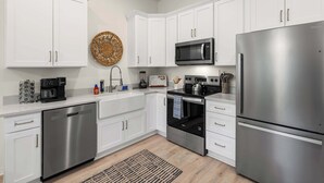 Una cocina moderna con armarios blancos, electrodomésticos de acero inoxidable y una isla central.