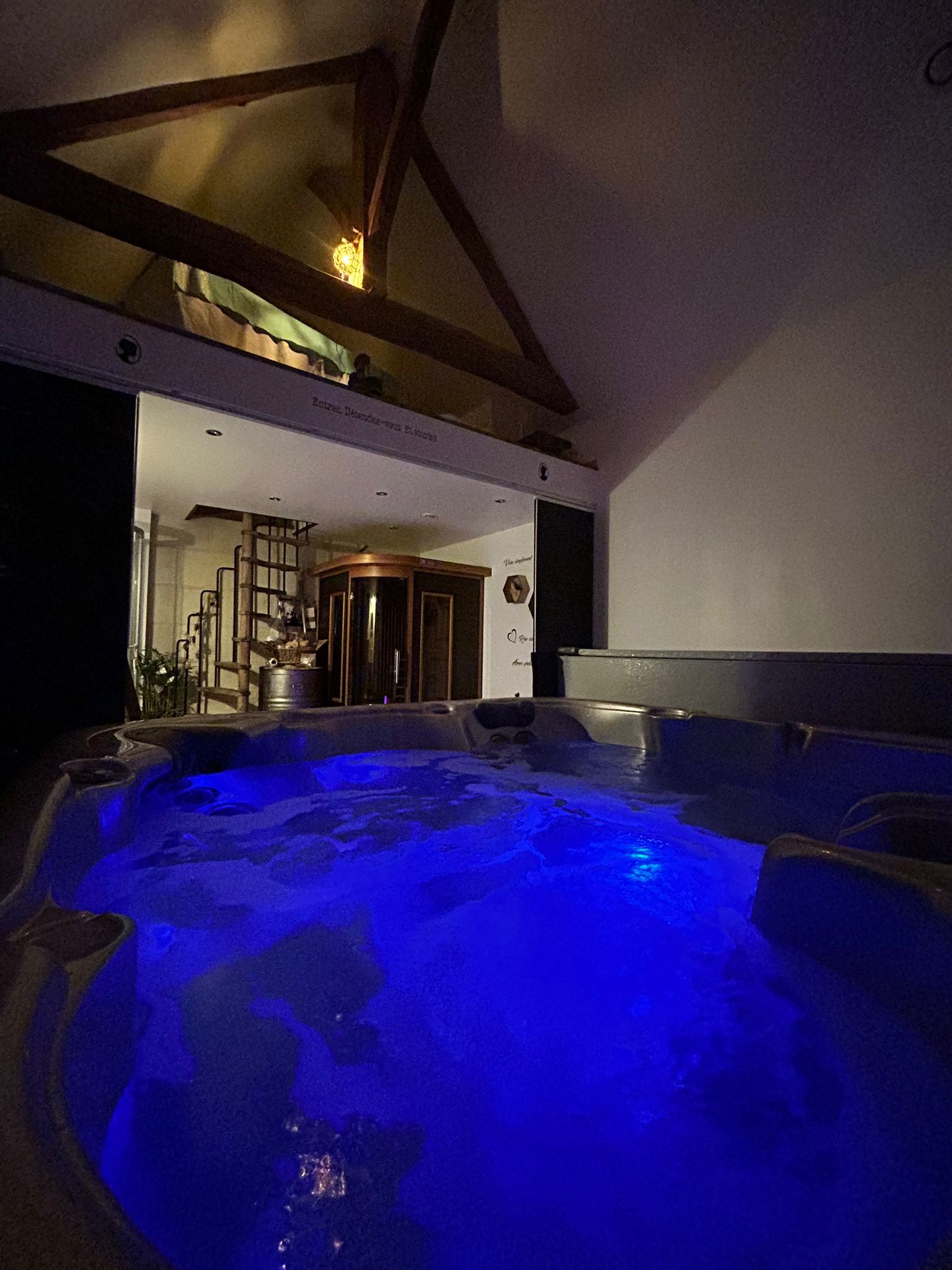 Un jacuzzi avec un éclairage bleu, un escalier et une pièce avec une porte.