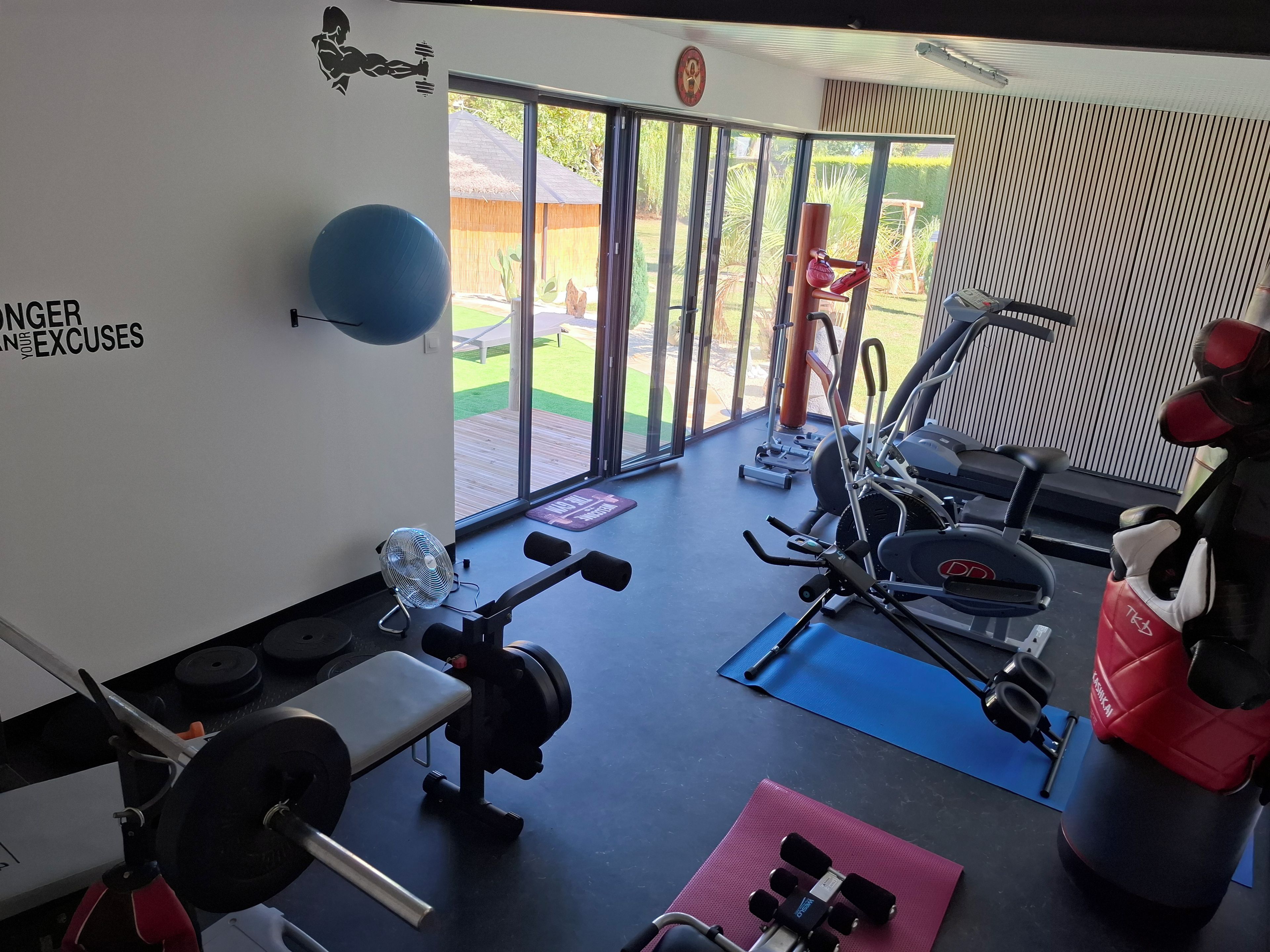 A gym with exercise equipment, a fan, and a view of a backyard.