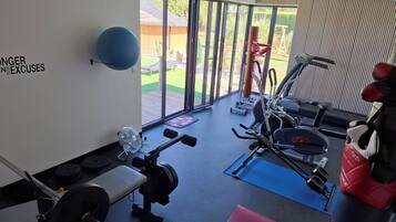 A gym with exercise equipment, a fan, and a view of a backyard.