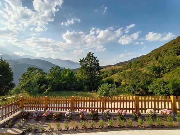 A scenic view of a mountainous landscape with a wooden fence and flower beds.