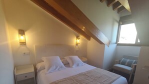 Ein Schlafzimmer mit Bett, Nachttischen, einem Sessel und einem Fenster.