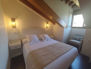 A bedroom with a bed, nightstands, a chair, and a window.