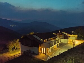Une maison moderne dotĂ©e dâun vaste patio, dâun grand garage et offrant une vue sur les collines environnantes.