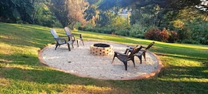 Un espacio de estar al aire libre circular con un brasero y cuatro sillas Adirondack.