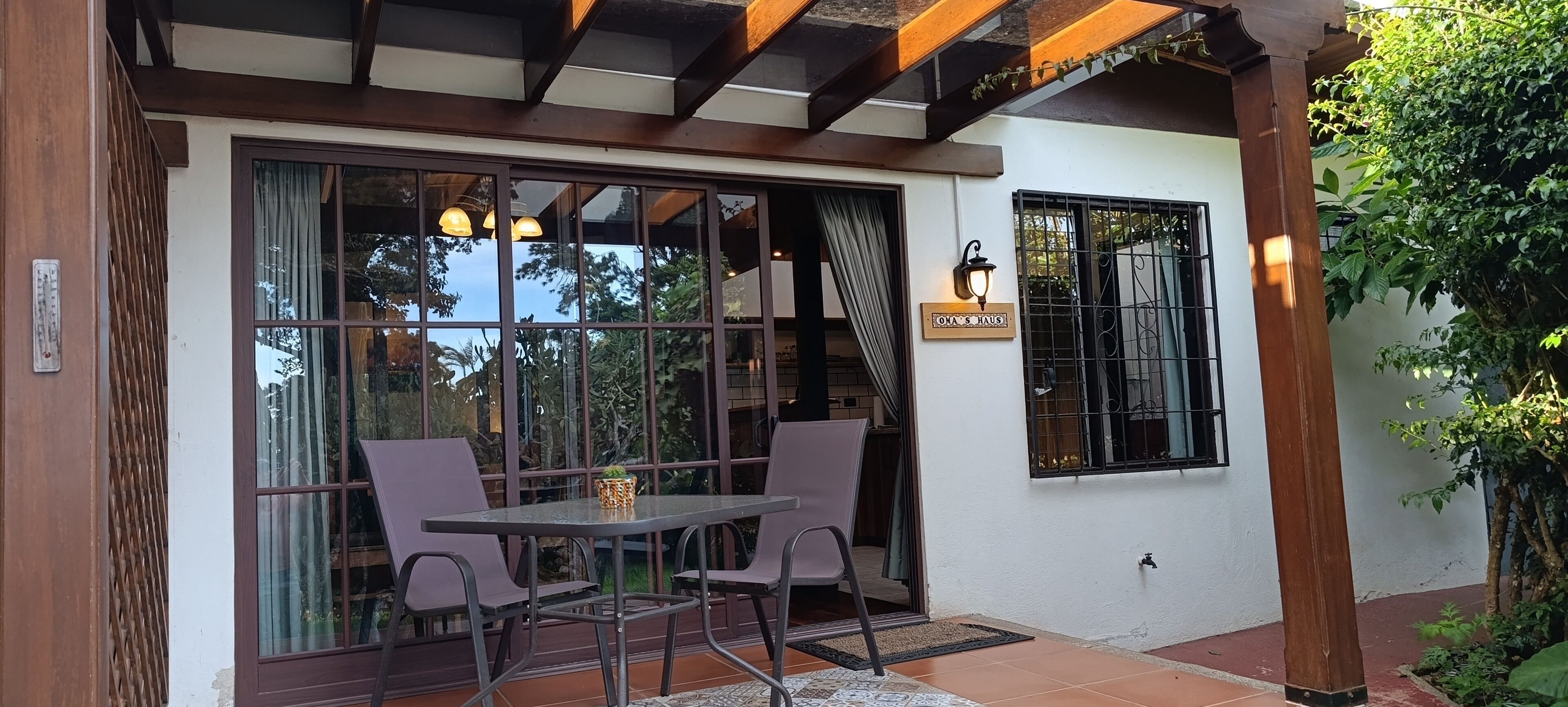A patio area with a table and chairs, a glass door, and a wall-mounted light fixture.