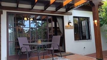 A patio area with a table and chairs, a glass door, and a wall-mounted light fixture.