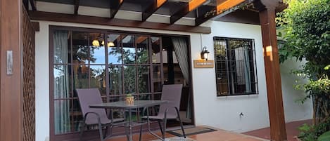 A patio area with a table and chairs, a glass door, and a wall-mounted light fixture.