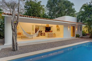 A modern house with a swimming pool, a hammock, and a kitchen area.