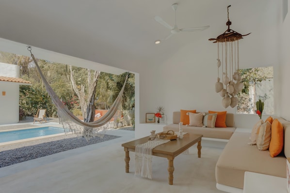 A modern living room with a hammock, a pool, and a large window.