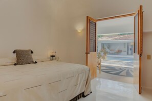 A bedroom with a bed, bedside table, lamp, and a view of an outdoor area.