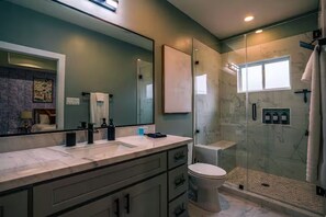 Une salle de bain moderne avec un grand miroir, une cabine de douche, des toilettes et un meuble-lavabo.